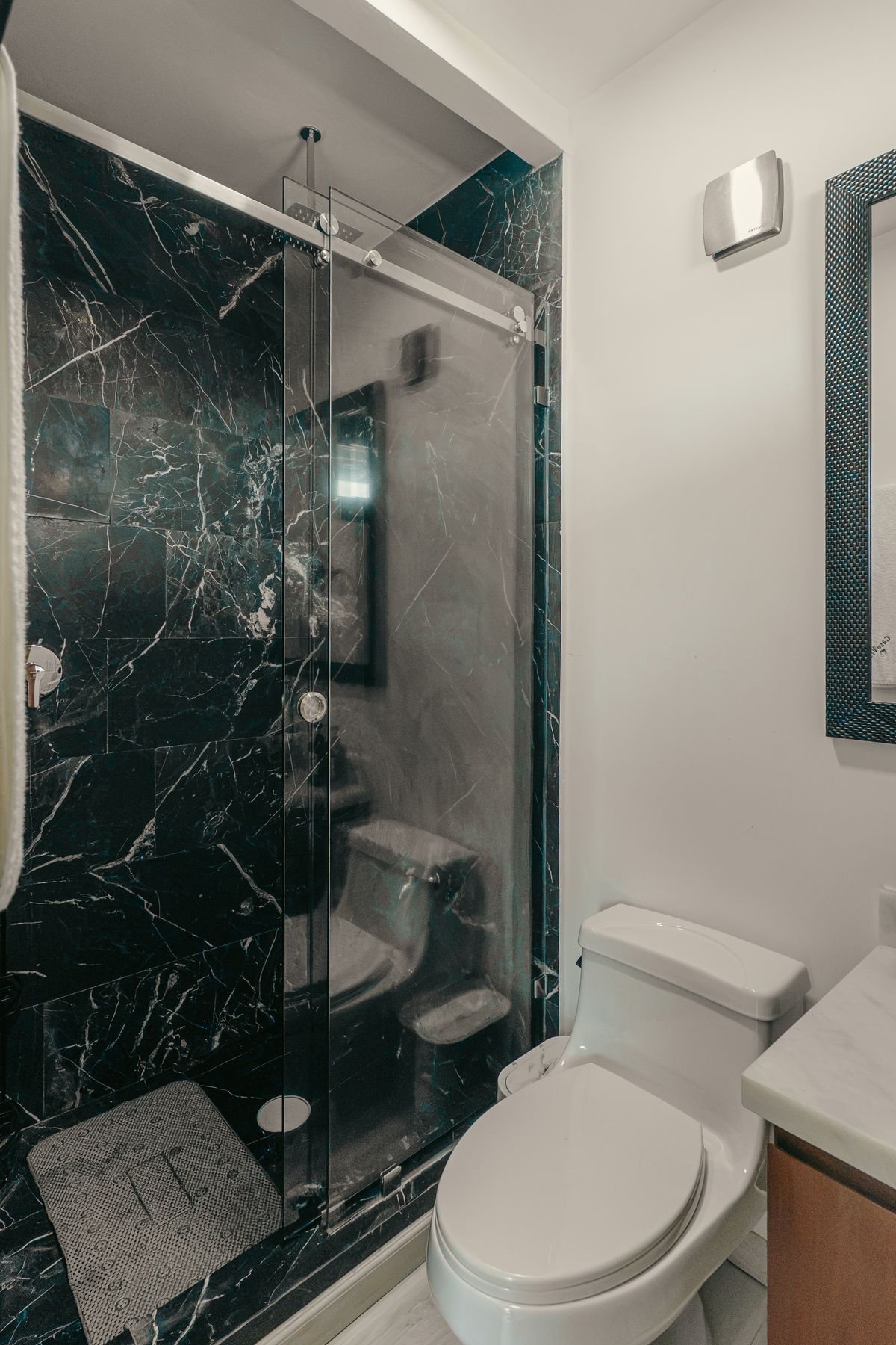 Baño con regadera y acabados en mármol negro