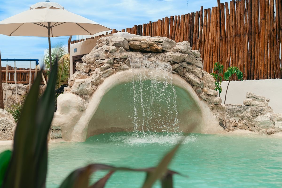Gruta con cascada integrada en la alberca de la casa de playa