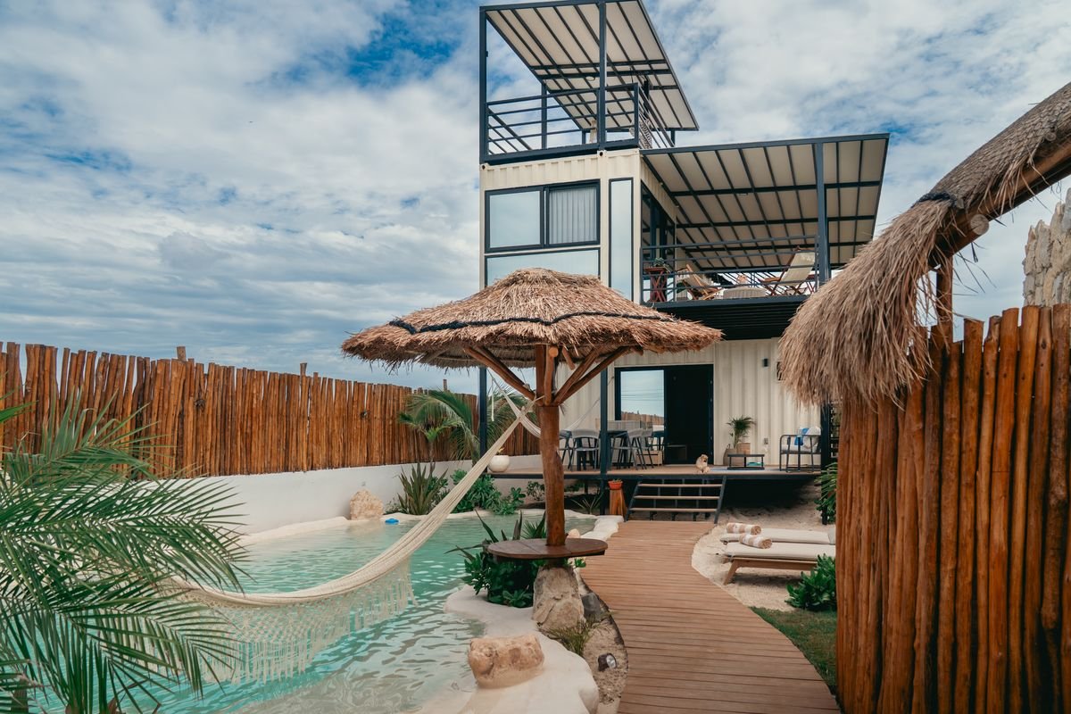 Hamaca y palapa junto a la alberca con la casa al fondo