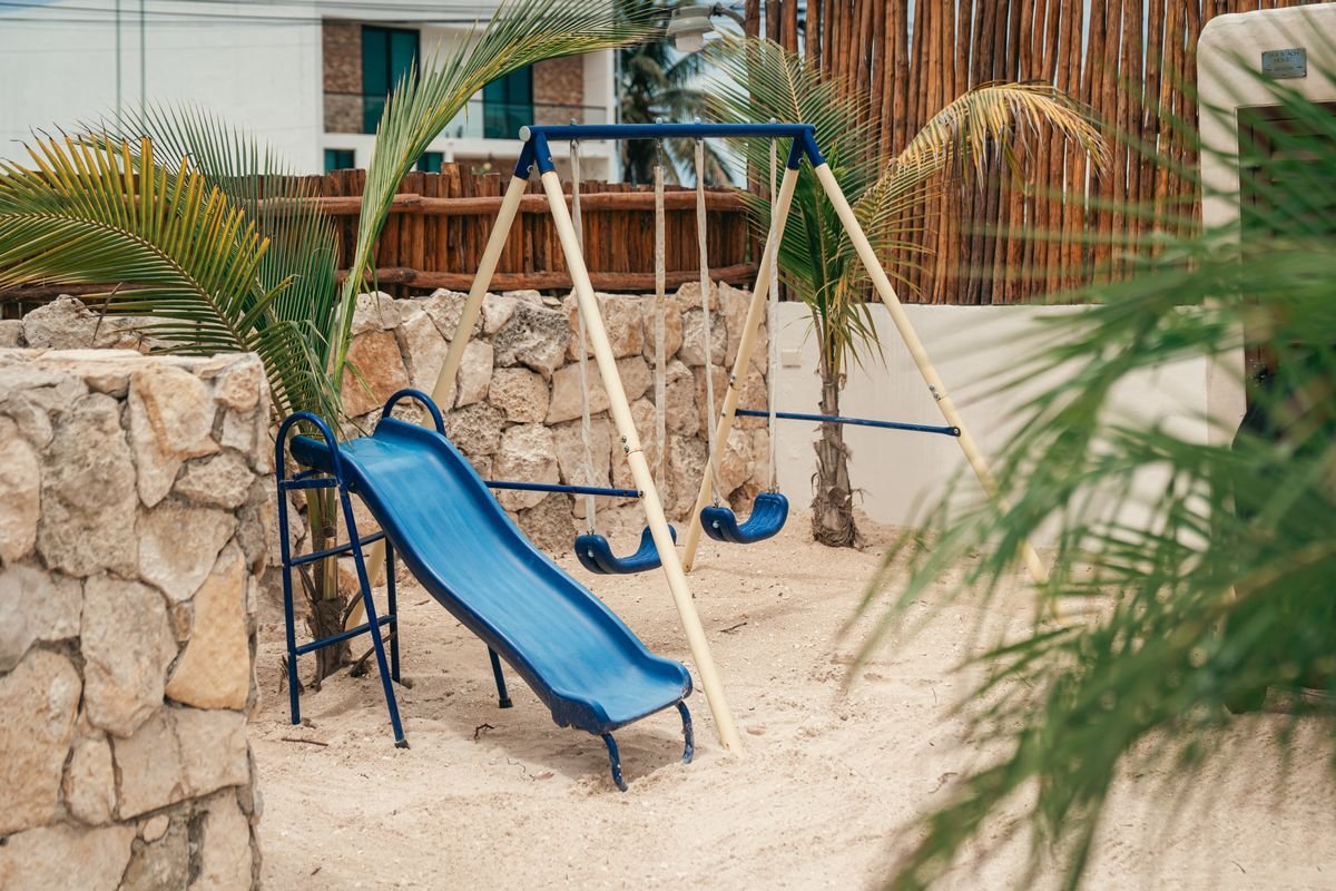 Juegos infantiles con resbaladilla y columpios en el jardín